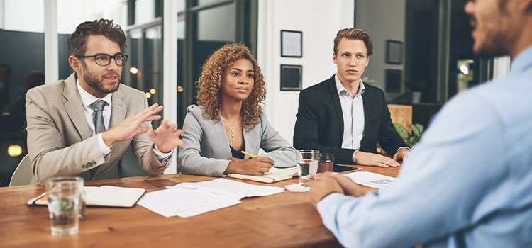 Managers and other professionals talk at a table. 
