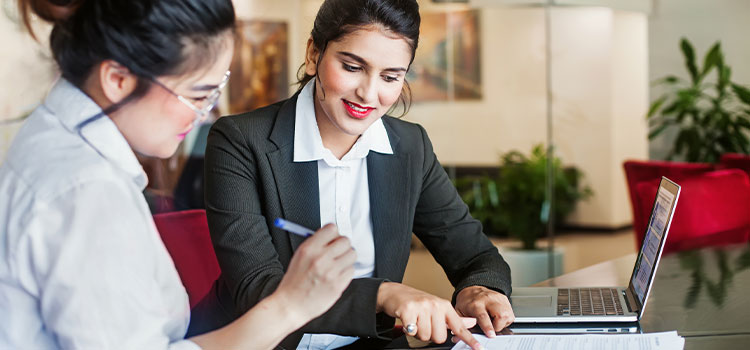 a manager reviews a staffer's work at a desk