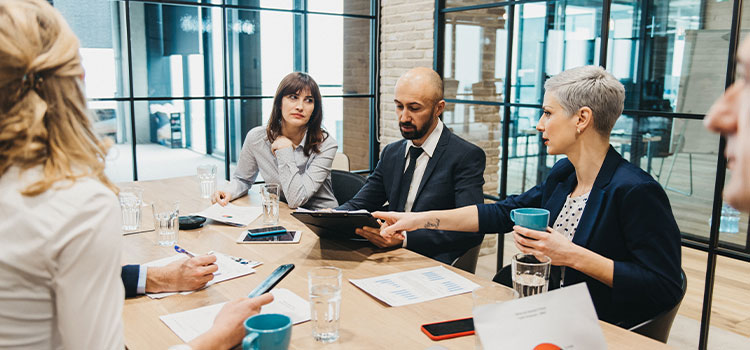 A manager goes over reports with staff at a conference tableer rex