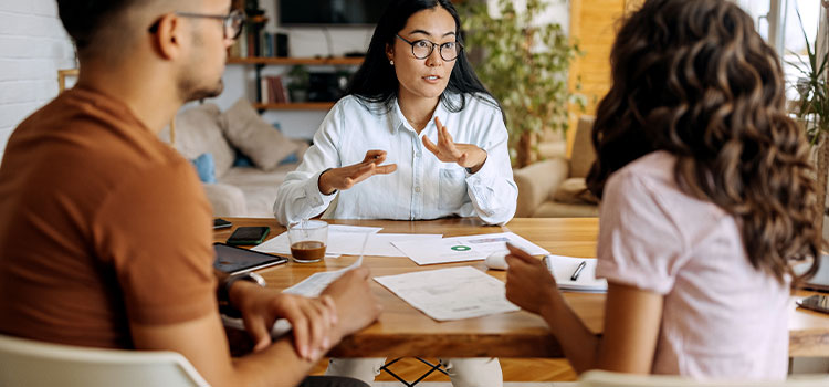 a professional  woman consults with two clients in an office