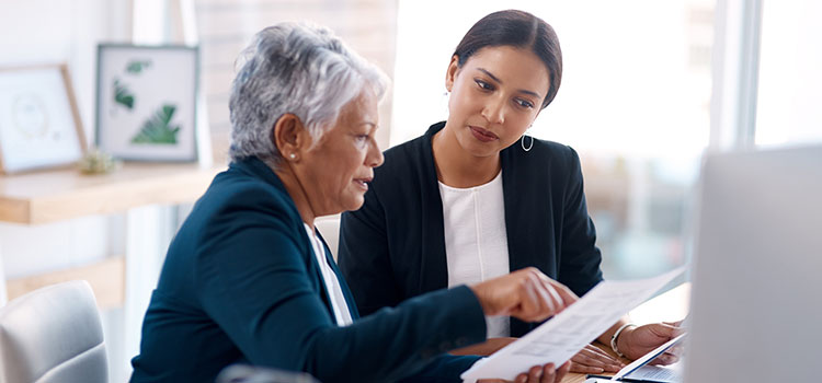 two businesswomen leaders review client accounts files