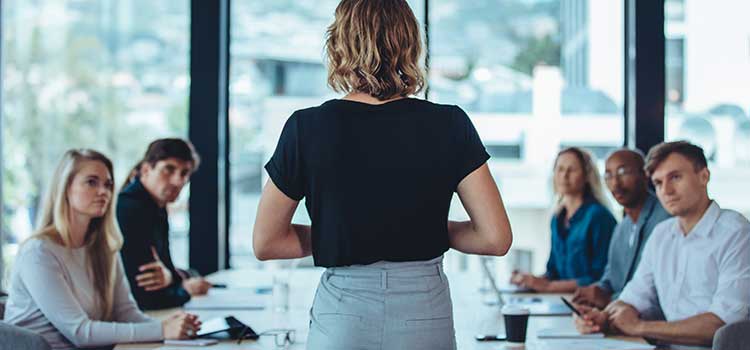 woman stands up and heads business administration meeting in modern office