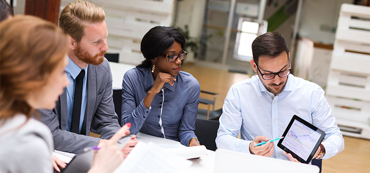 a man shares information on a tablet with coworkers during a meeting