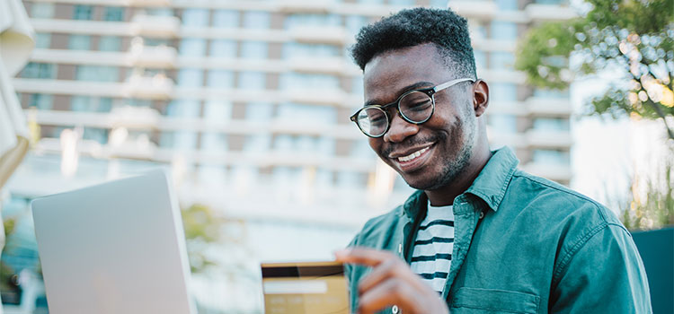 A man smiles as he reads on his laptop