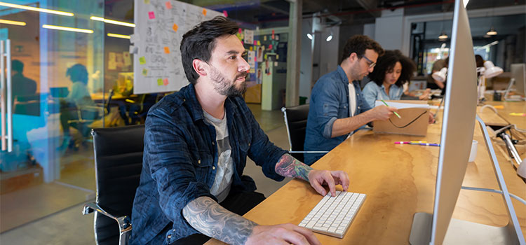 A man works at a desk in his office alongside workers