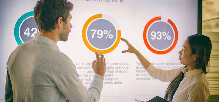 two financial analysts discussing data on projector