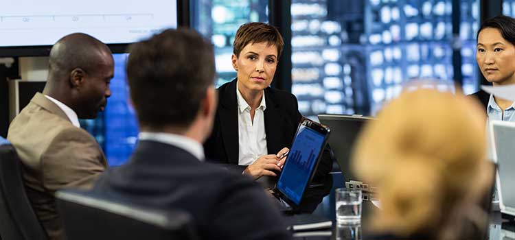 woman leading meeting with line graphs on screen in background