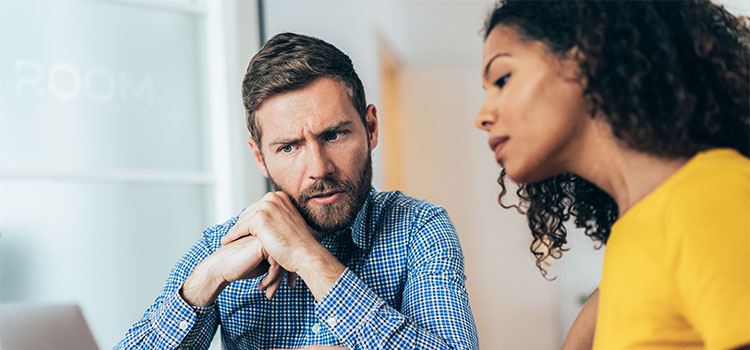 A man listens as a woman explains information to him