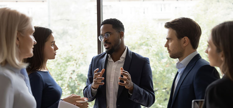 A leader talks to his staff as they stand around him.