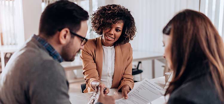 female insurance agent reviews policy with two customers