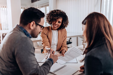 female insurance agent reviews policy with two customers