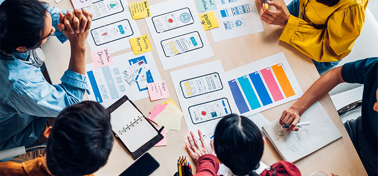 A  team works on a project at a table with drawings and sticky notes