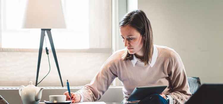 Woman works on laptop and takes notes