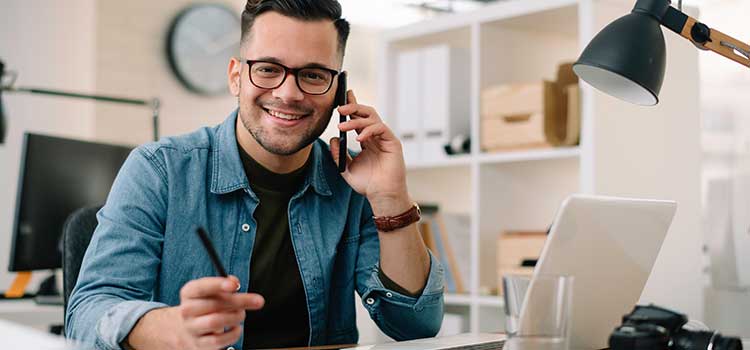 marketing manager on cellphone at office desk with laptop