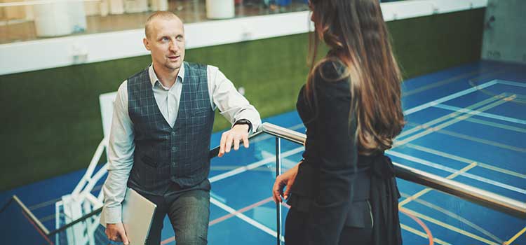 man and woman on indoor tennis court discussing business
